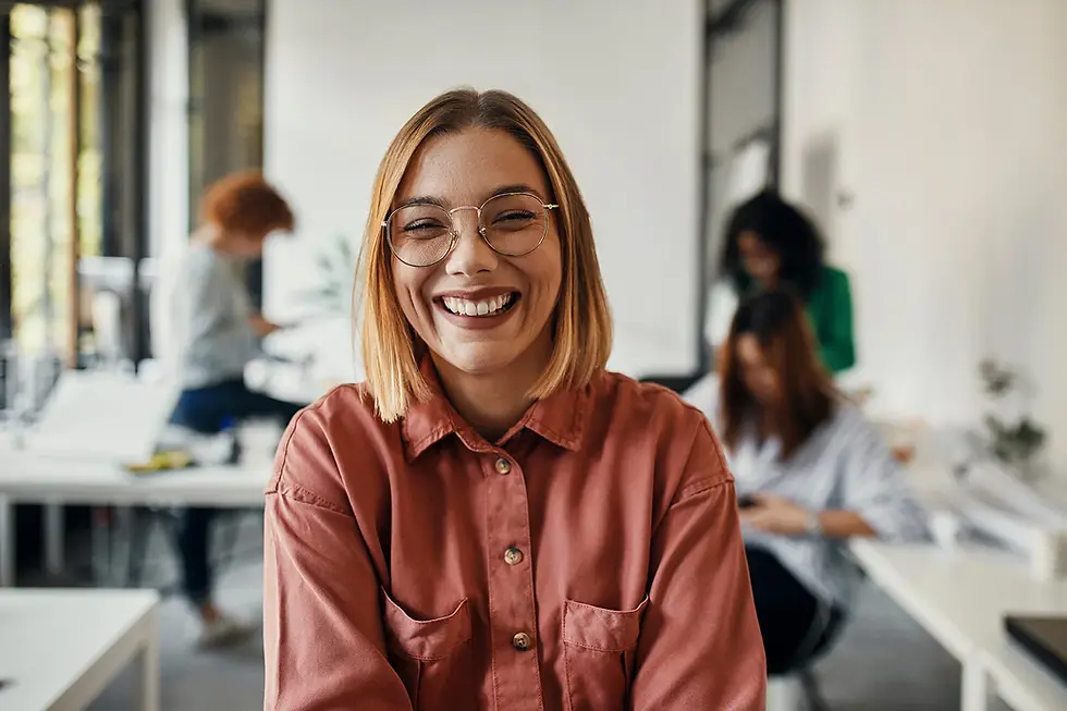 Smiling woman with glasses in a modern office setting.
