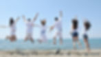 People jumping for joy on a beach overlooking the ocean.