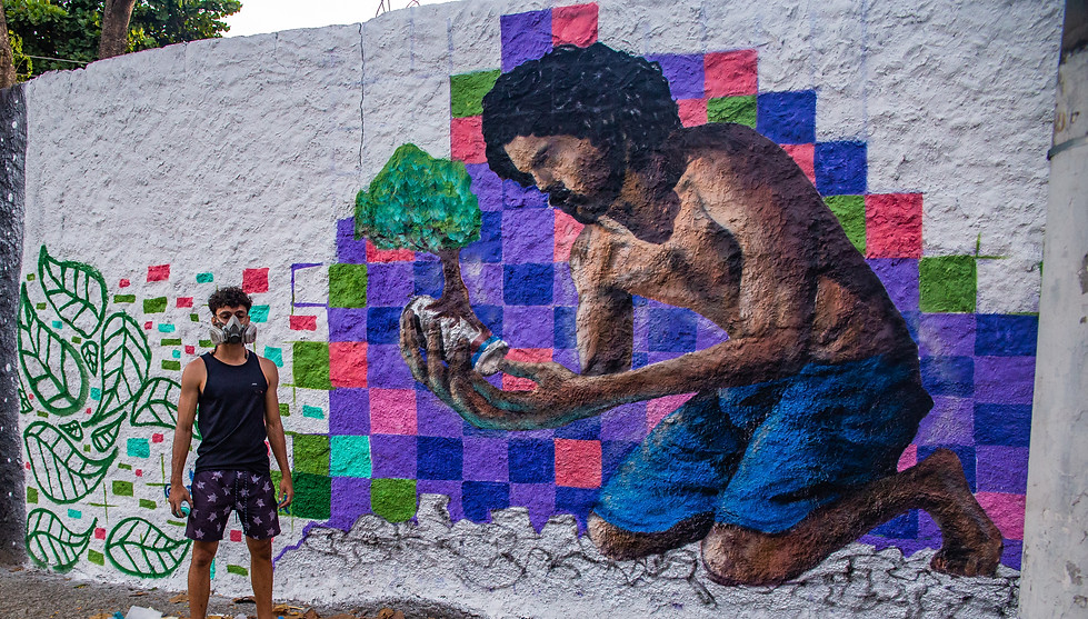 Artista Smith Arte em frente ao seu painel (audiodescrição abaixo)