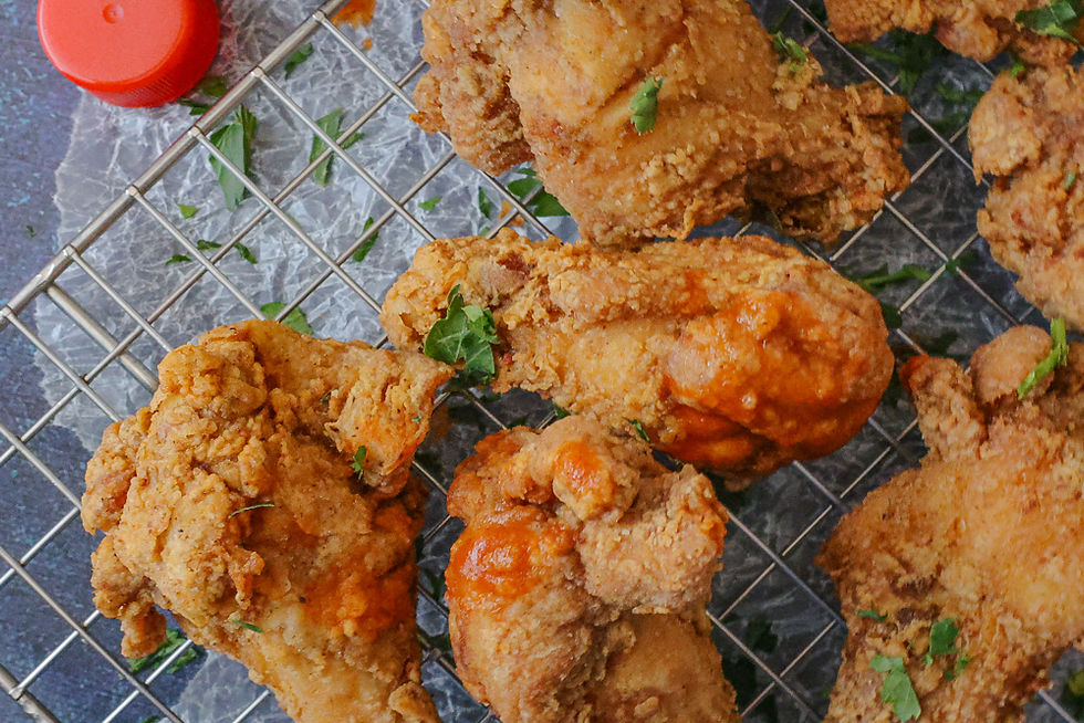 Fried chicken wings with splashes of hot sauce.
