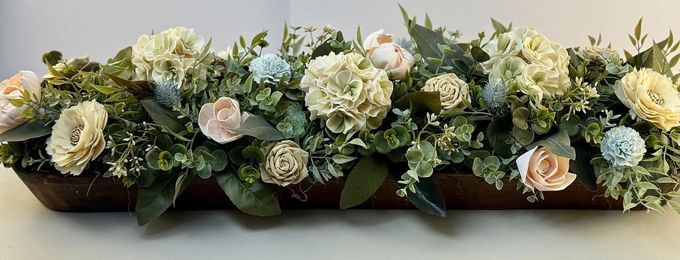 Cream sola wood hydrangeas, blush roses and light blue accent flowers in a long wooden dough bowl