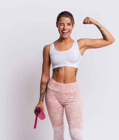 fit-blond-woman-with-perfect-smile-in-stylish-sportswear-looking-at-camera-and-holding-bot