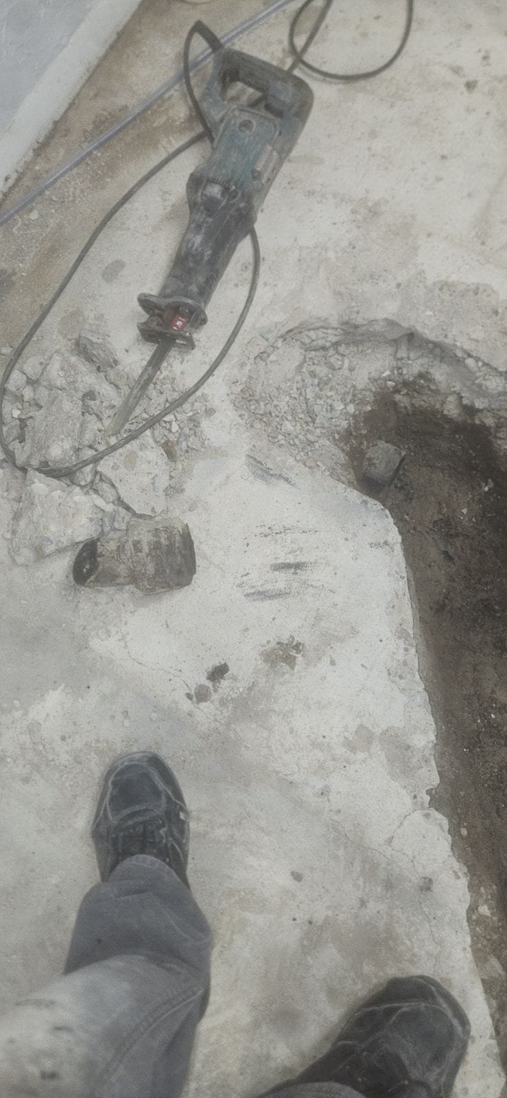 Image of a worker clearing debris from a storm drain. Maintaining clear storm drains prevents flooding and costly repairs. Search 'drain repair near me' to find local services for drain maintenance. Keep in mind that neglected storm drains can lead to septic drain field issues, impacting 'septic drain field repair cost'.