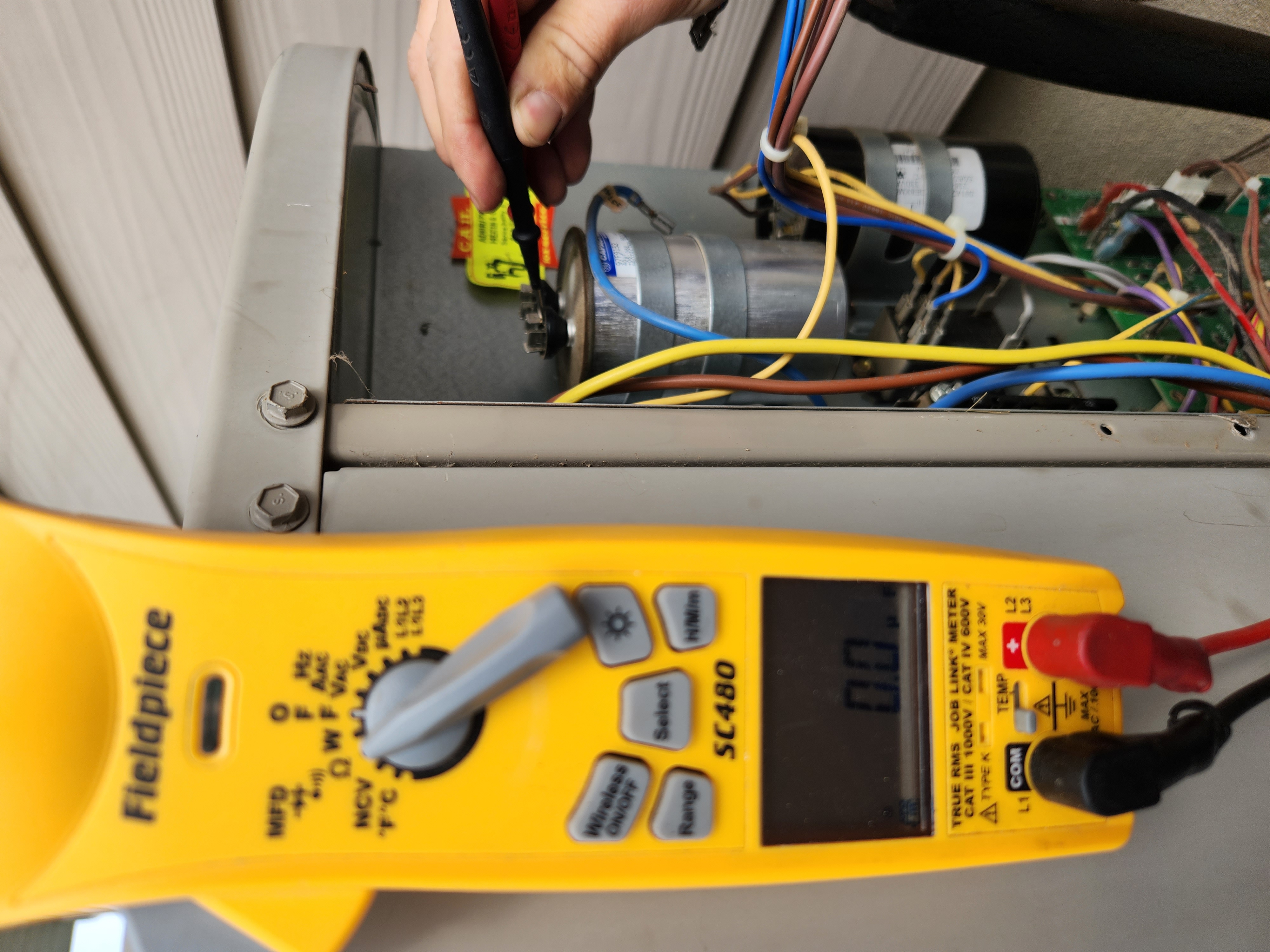 Image of a technician troubleshooting an air conditioner, possibly as part of a spring AC tune-up. The focus is on identifying potential issues like a condenser not turning on, ensuring optimal cooling performance for the summer season.