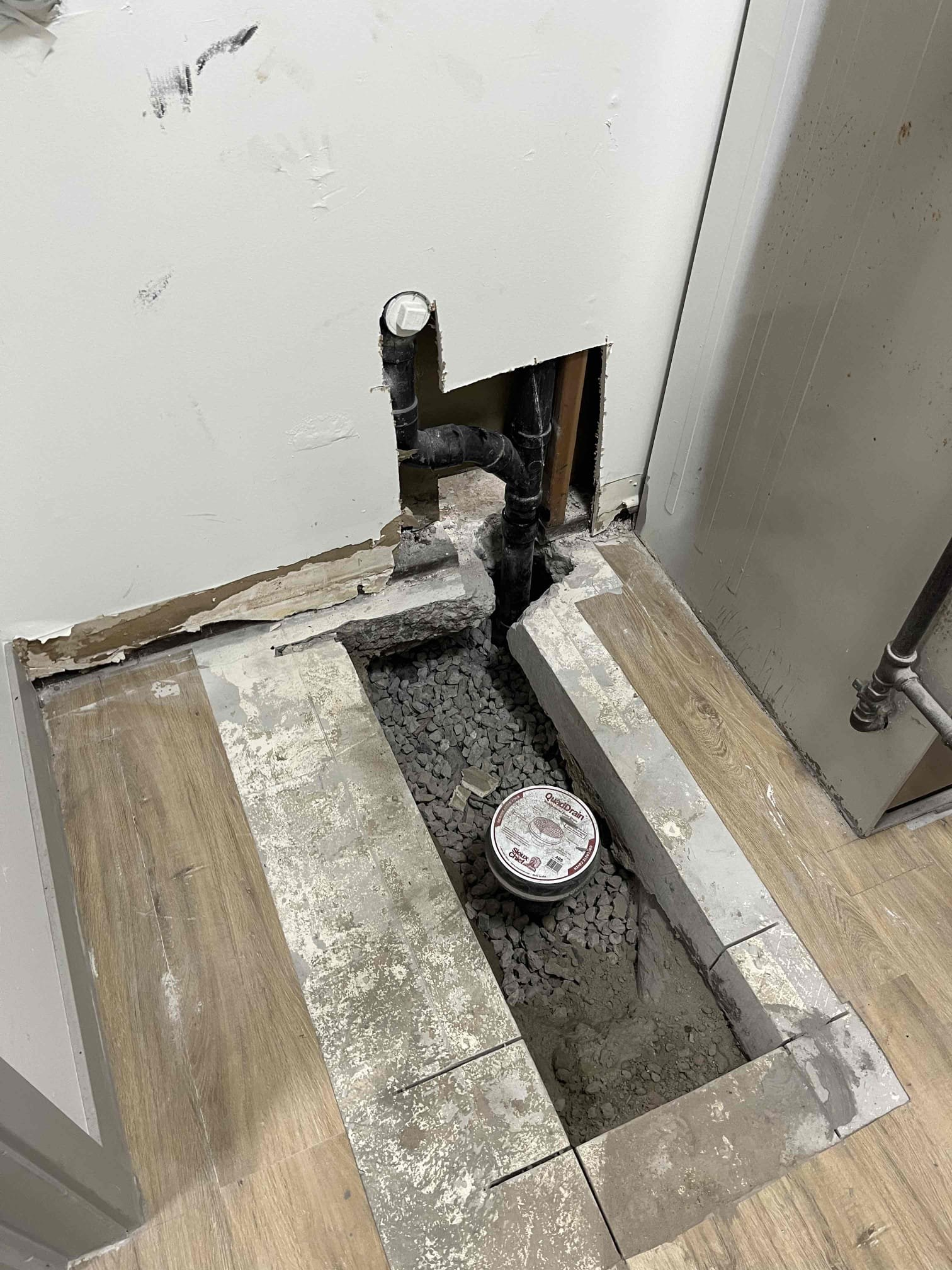 Professional basement drywall water damage repair near a basement P-trap, highlighting the need for water damage services. Visible drywall damage indicates potential plumbing issues.