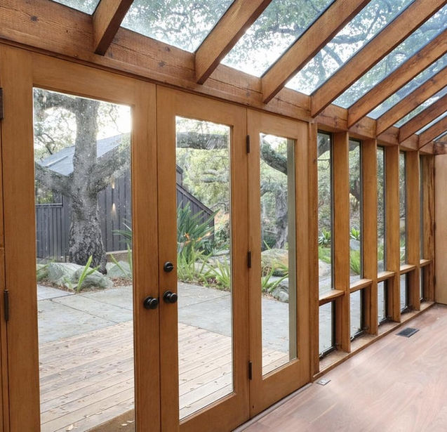 Light-filled sunroom with floor-to-ceiling glass doors in a Santa Barbara modern residence, designed for indoor-outdoor living and connection to nature