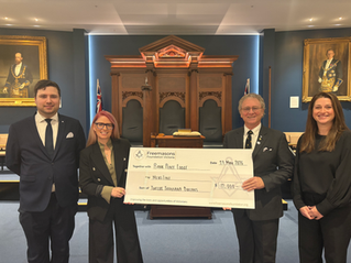 Two men and two women stand proudly holding a novelty cheque in a Masonic Lodge Room.