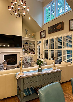 Spotless, professionally cleaned living room with high ceilings, chandelier, organized built-in shelves, clean fireplace, and