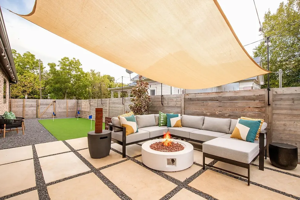 Modern backyard patio with fire pit, sectional sofa, and shade canopy for group getaway entertaining in Austin
