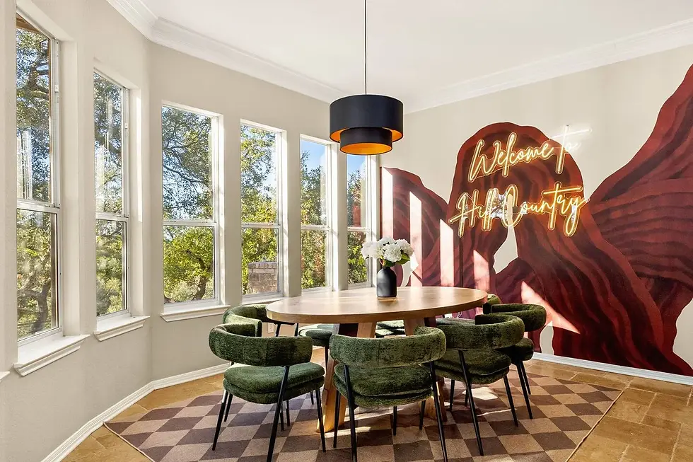 Modern dining room with round wooden table, green chairs, rose mural and neon sign in Moulin Rose, a Dripping Springs large