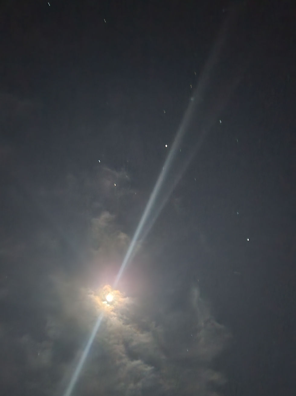 Moonbeams shining through a dark night sky with stars.