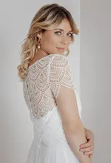 Eine blonde Frau in einem weißen Oberteil, steht lächelnd. lieben.tanzen.lachen.