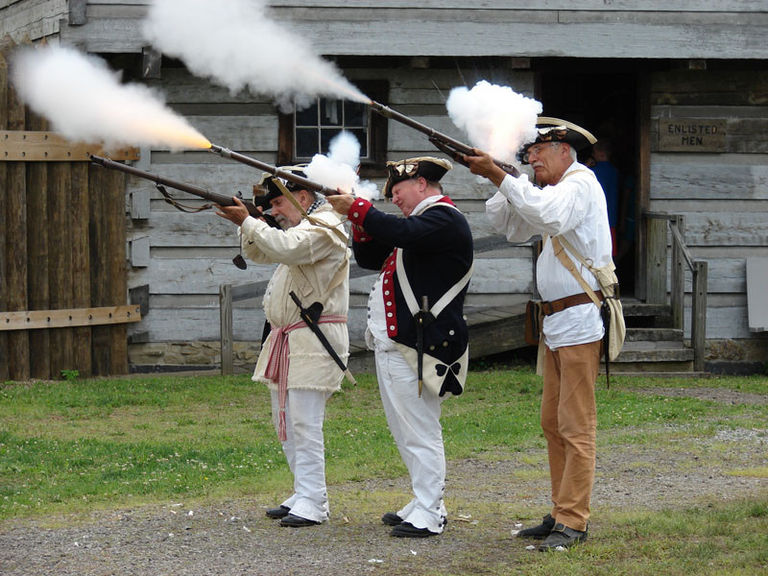 Three men dressed as soldiers shooting rifles