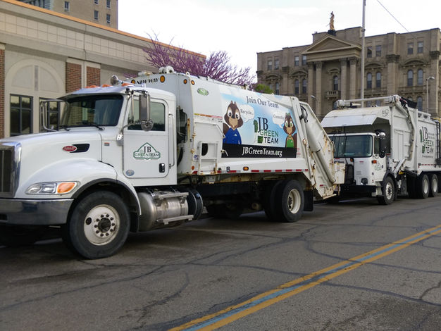 Three recycling trucks driving through a town