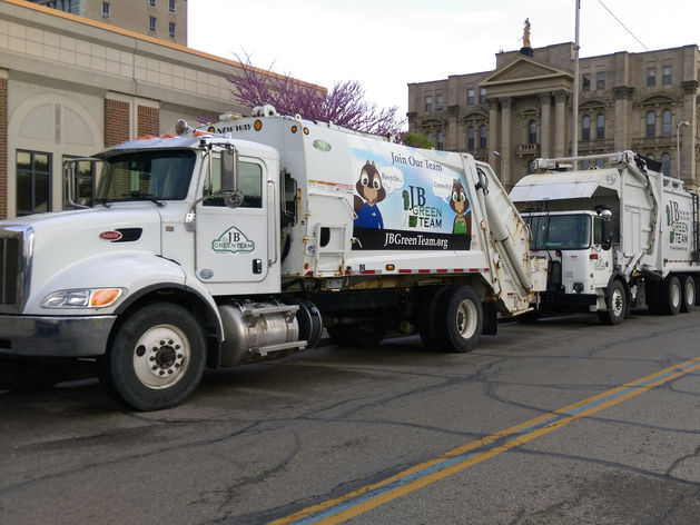 Three recycling trucks driving through a town