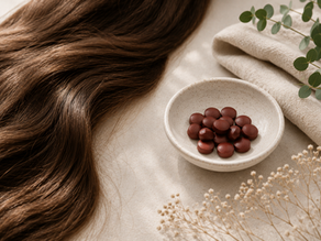 Low iron and hair loss concept image showing healthy brown hair beside a bowl of iron tablets on a soft neutral background.