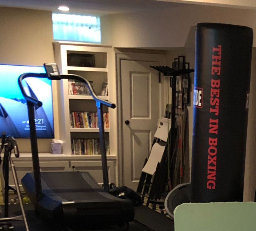 basement workout area in a home, with a treadmill, bookcases, and boxing equipment
