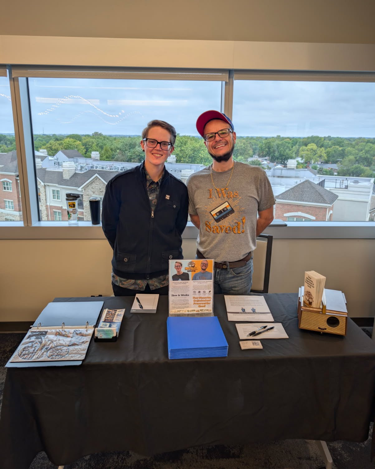 Tabi and Jaycee are standing behind their table with the Upper Arlington skyline behind them