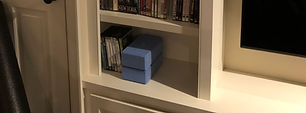 a small shelf contains yoga blocks, dvds, and music for working out