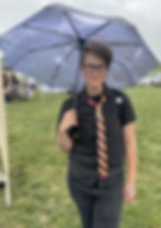 Tabi, Owner/Operator of Organization Pending at Rainbow UA Pride 2023 - wearing all black with a rainbow tie, holding an umbrella and smiling