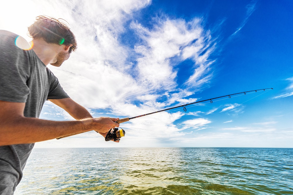 Young man casting fishing line
