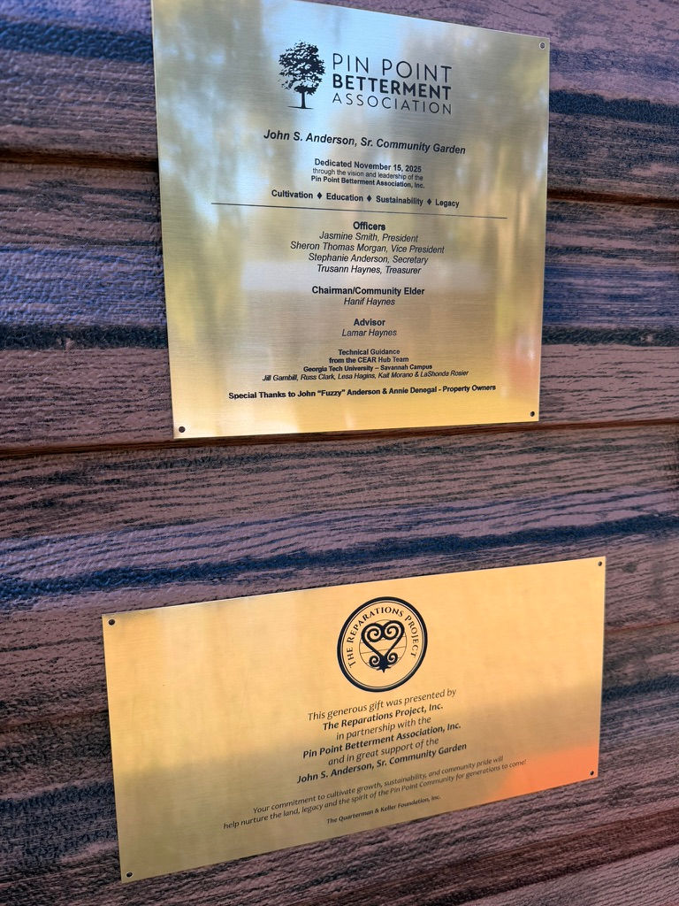 The newly installed shed at the John Anderson, Sr. Community Garden features plaques honoring The Reparations Project's donation and the guidance of Georgia Tech's CEAR Hub members, marking a commitment to community growth and sustainability.