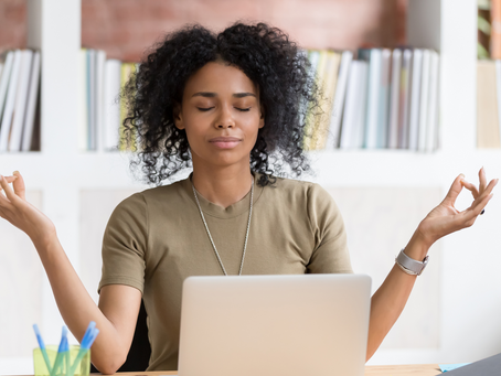 Mujer de negocios negra con expresión calmada, meditando en su oficina.