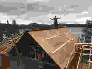 A Man on top of a diy cabin roof build