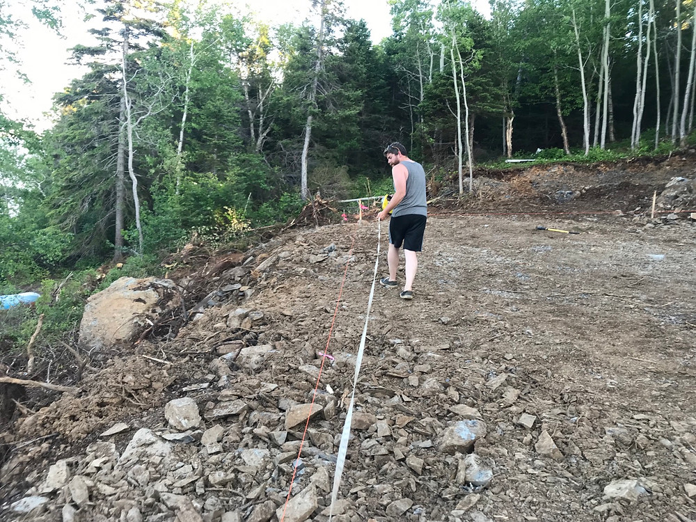 Using a measuring tape to grid out the location of our foundation for our cabin