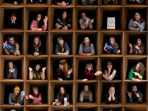 Bert Nash team members posing in brady-bunch-style cardboard boxes. Some are high fiving, some are holding Bert Nash Center pennants.