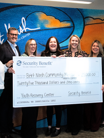8 people from the Bert Nash Center and Security Benefit hold a large check for $25,000.