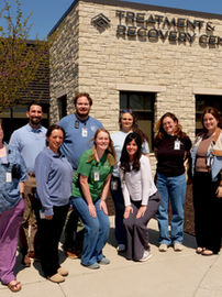 A group of TRC team members smile in front of the building.