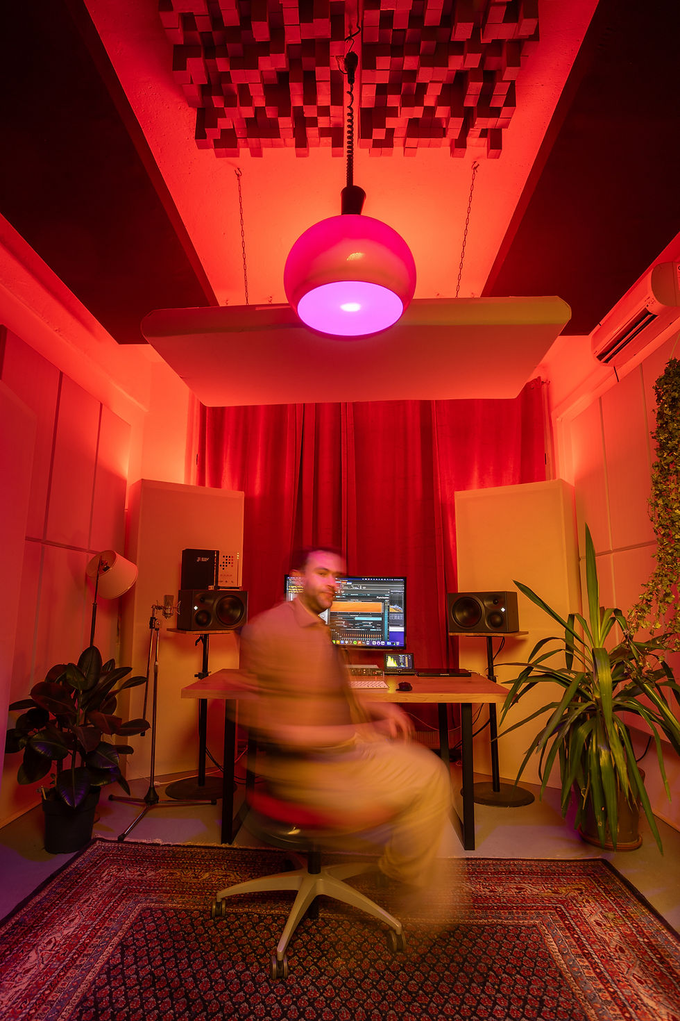 Wide-angle view of a compact recording room with a keyboard, electric guitar, studio monitors, and handwritten song sections on a music stand.
