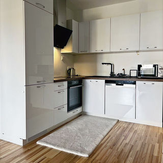 Weiße Hochglanzküche mit Holzarbeitsplatte in L-Form Wien