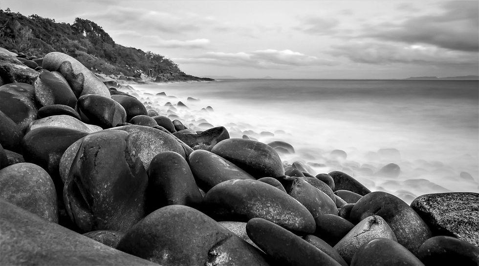 Black & white photo of boulders on a Noosa beach after long exposure