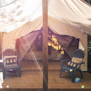Four Corners safari tent illuminated by soft sunlight, trees peeking around the edges of the canvas.
