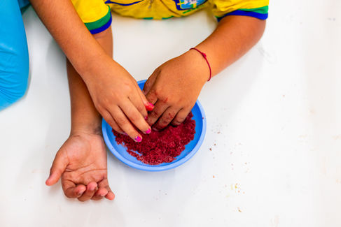 Mãos de crianças mexendo em massinha caseira em atividade lúdica sobre alimentos