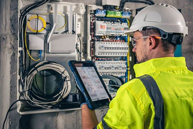 man-electrical-technician-working-switchboard-with-fuses-uses-tablet-1.jpg