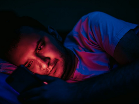 A teenage boy sitting alone at night looking at his phone, representing the experience of young men encountering online manosphere content