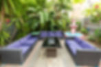 Lush tropical outdoor lounge at Upper Deck Hotel & Bar on South Padre Island, featuring purple cushi