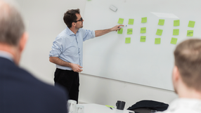 Undervisning mand peger på post its på tavle