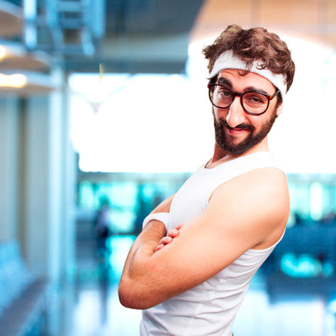An idiotic man wearing glasses standing in a gym