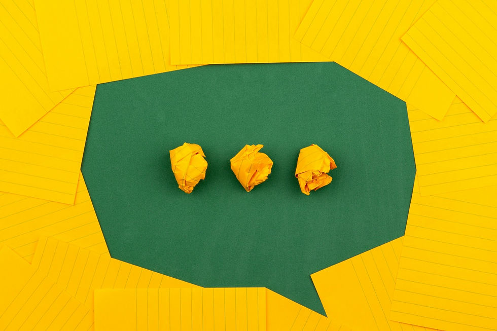 Three crumpled yellow paper balls inside a green speech bubble shape, surrounded by neatly arranged yellow lined paper sheets