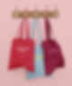 mockup-of-three-customizable-tote-bags-hanging-against-a-solid-color-wall-41717-r-el2.png