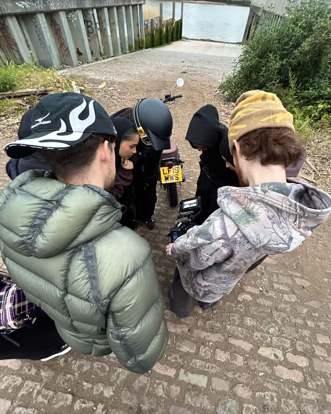 Behind-the-scenes moment from Gen-Z streetwear shoot with group gathered around motorcycle