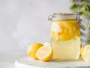 Bottle of homemade limoncello with fresh lemons and glasses filled with ice