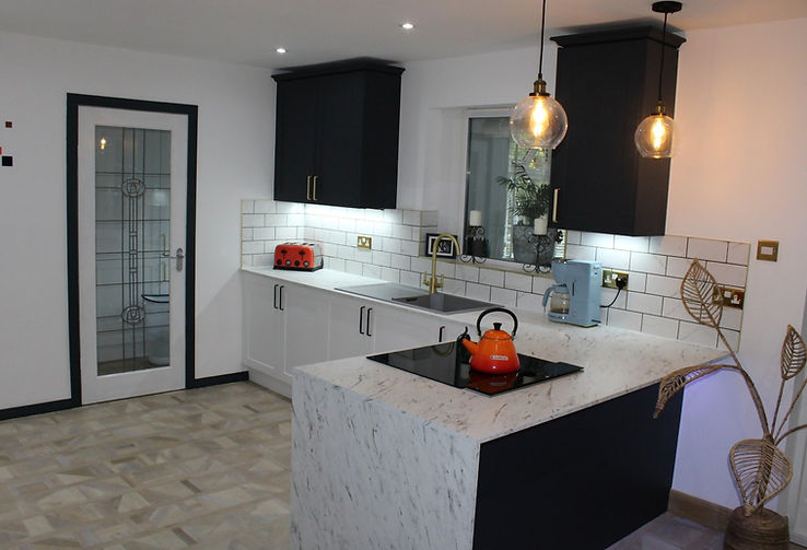 Fitted kitchen with white cupboards and marbled worktops