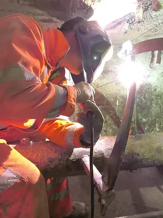 Man in orange hi-vis welding a machine