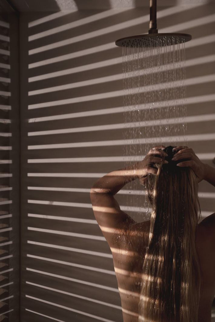 Künstlerische Social Media Content Aufnahme einer Frau in der Dusche