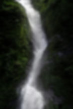 Ein großer Wasserfall zwischen grün bewachsenen Felsen.